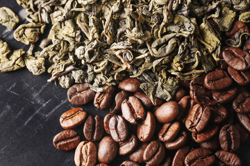Coffee beans and green tea leaves. Aromatic ingredients on dark background. Roasted brown beans and loose dried herbal leaves. Natural caffeine sources for brewing hot energizing beverages.