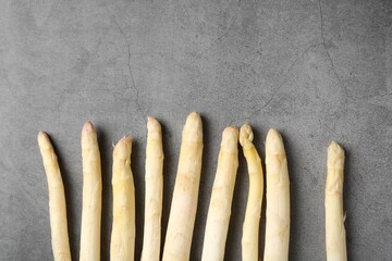 Many raw asparagus spears on grey table, flat lay. Space for text