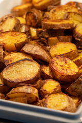 Close-up of rustic fried potatoes, crispy country-style potato wedges, golden roasted potato dish