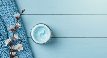 Blue Skincare Cream Jar with White Flowers and Knit Fabric on Pastel Surface