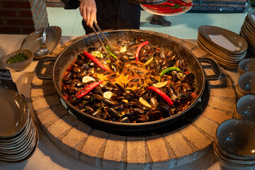 Seafood cooking in large pot with peppers and savory sauce, traditional preparation of fresh...