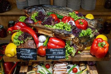 Original buffet table setup with Romanian cuisine featuring dried fish, vegetables, spreads, and wooden walls creating rustic dining atmosphere