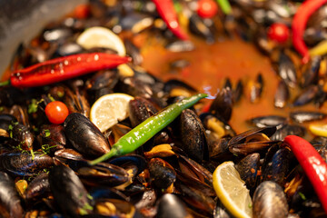 Oysters or mussels cooking in a rich sauce with red and green peppers. A flavorful seafood dish captured in the heat of preparation, showcasing vibrant colors, steam, and the freshness of Mediterranea