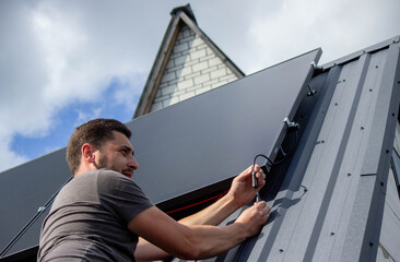 Technician Installing Solar Panels on Metal Roof