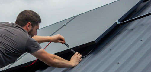Technician Installing Solar Panels on Metal Roof