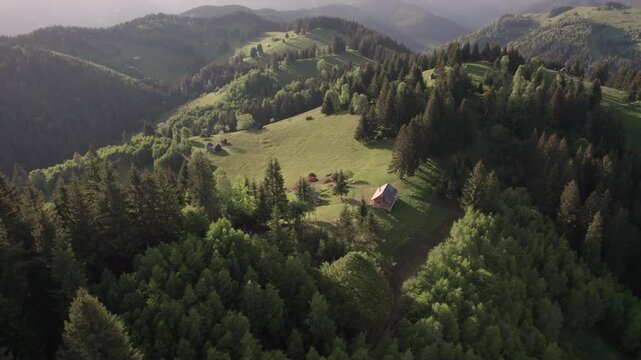 Aerial view of the Transylvanian village in the mountains, during summer. Sunset scene over the mountain valley in the Carpathian Mountains