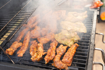 Meat is being cooking on a barbecue. Smoke is rising. It looks really delicious. Outdoor concept.