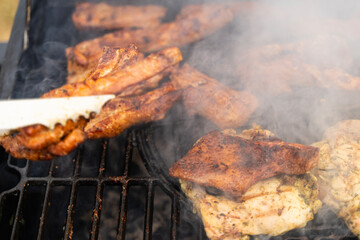 Meat is being cooking on a barbecue. Smoke is rising. It looks really delicious. Outdoor concept.
