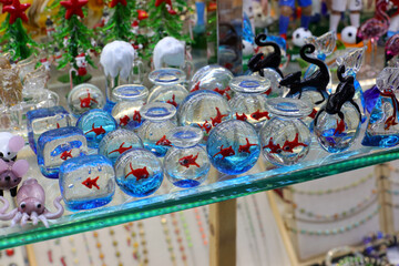 beautiful glass ornaments with animals and bowls with goldfish for sale in the souvenir shop in...