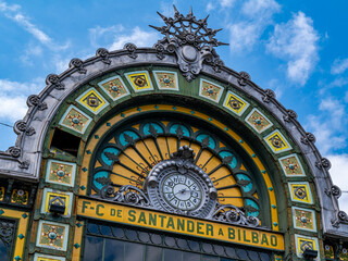 Iconic facade of the Santander train station in Bilbao, featuring ornate details, historic architecture, and city life on a clear day in the Basque Country.