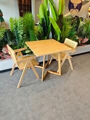 The clean lines and natural wood finish of the furniture complement the vibrant green plants that surround the seating area, creating a fresh and inviting atmosphere.