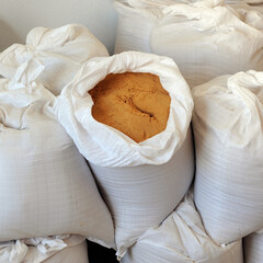 Raffia sacks filled with sand for construction stacked inside a room of a house being renovated and refurbished. Building materials. Square format image
