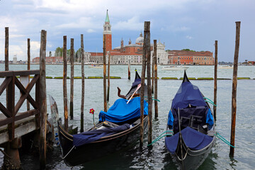 moored gondolas the typical boats in venetian Lagoon in VENICE In Northern Italy and Church of...