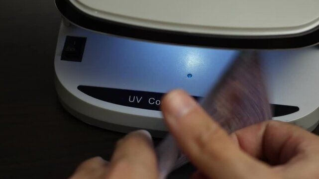 Examination of malaysian ringgit (MYR) cash money with UV counterfeit detector. Concept of authenticity check, fight against counterfeiting of banknotes, anti fraud measures in Malaysia. Close up view