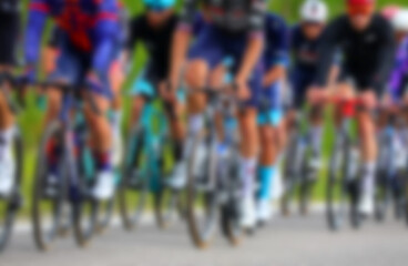 Fototapeta premium Intentionally blurred group of many professional cyclists energetically pedaling on racing bikes during a competitive race