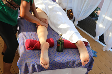 hands of masseuse massaging young woman s thighs during therapeutic session in wellness spa