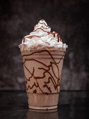 Chocolate milkshake served in a clear glass on a dark background. Isolated drink