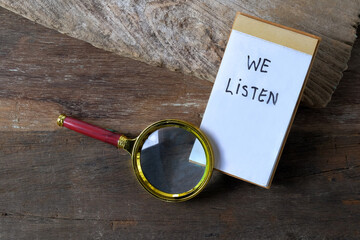 We listen text written on a notebook and magnifying glass.