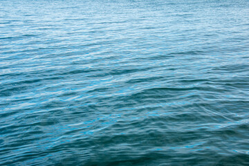 Water background of lake Traunsee in the Alps. The colorful texture of reflections of a clear mountain lake. Texture of water with reflections.
