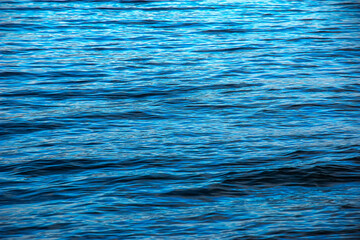 Water background of lake Traunsee in the Alps. The colorful texture of reflections of a clear mountain lake. Texture of water with reflections.
