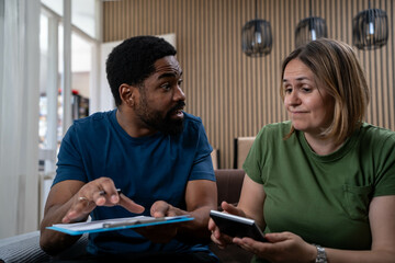 Interracial couple at home looking worried, financial stress, unpaid bills, rising food prices
