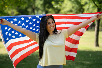 Beautiful woman holding USA flag outdoors, patriotic expression, celebrating Independence Day,...