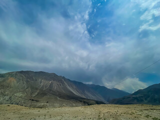 Majestic mountain landscape photographed in Chilas, Pakistan. Dark clouds hover over rugged peaks, creating a dramatic and atmospheric view of northern Pakistan’s natural beauty.
