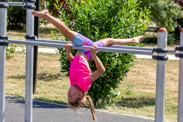 Child performing an upside-down split on a horizontal bar