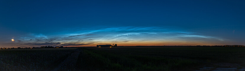 Fototapeta premium Panorama of noctilucent clouds (NLC) over the wide open Dutch countryside on a clear evening in late June.