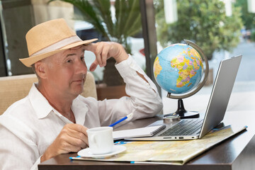 Experienced freelancer working on educational projects at a cafe with a globe and laptop
