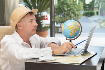 Freelancer working on a laptop with a globe in a cafe during the day