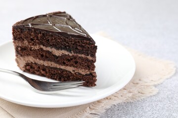 Piece of delicious chocolate cake and fork on grey table, closeup