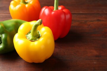 Ripe colorful bell peppers on wooden table, closeup