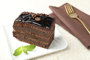 Piece of chocolate cake served with mint and fork on white table, closeup