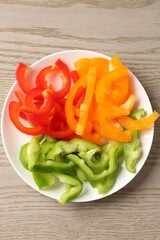 Slices of fresh colorful bell peppers on wooden table, top view