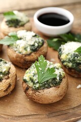 Tasty stuffed mushrooms served on wooden table, closeup