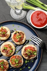 Tasty stuffed mushrooms served on black table, flat lay
