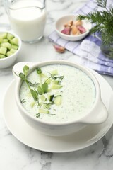 Tasty cucumber soup with dill, microgreens and ingredients on white marble table, closeup