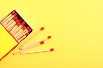 Matches and box on yellow background, flat lay. Space for text