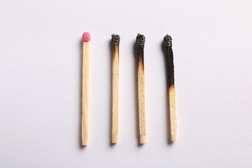Burnt and whole matches on light grey background, flat lay