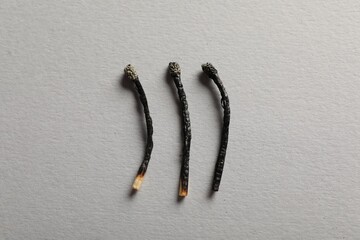 Burnt matches on grey background, flat lay