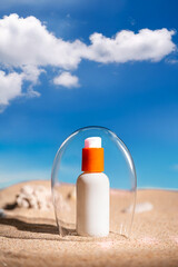 Sunblock or sunscreen in cosmetic tube under a glass dome as a symbol of sun protection on beach sand background. Summer vacation and skin care concept, spf uv-protect cosmetics. Skin health.
