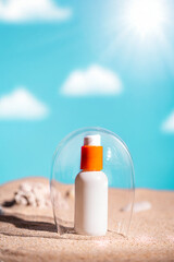 Sunblock or sunscreen in cosmetic tube under a glass dome as a symbol of sun protection on beach sand background. Summer vacation and skin care concept, spf uv-protect cosmetics. Skin health.