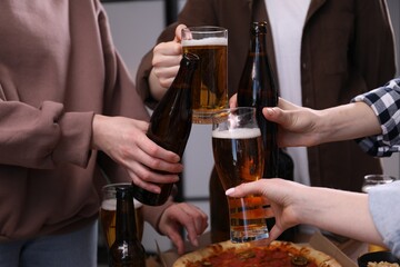 Friends clinking glasses of beer indoors, closeup