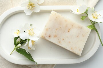 Soap bar and jasmine flowers on white table, flat lay