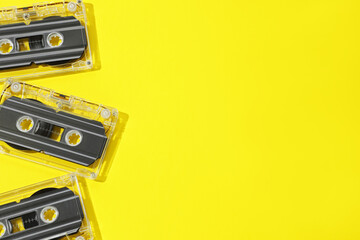 Audio cassettes with magnetic tapes on yellow background, flat lay. Space for text