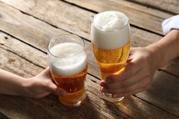 Friends with glasses of beer at wooden table, closeup