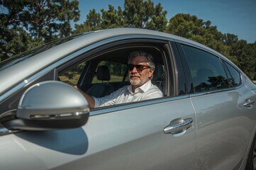 A happy man in his 60s driving a modern car