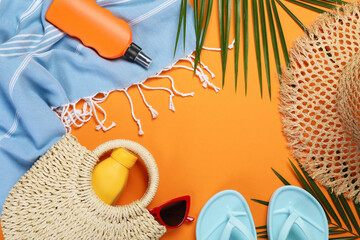 Frame of beach accessories and palm leaves on orange background, flat lay. Space for text