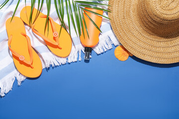 Beach accessories and palm leaf on blue background, flat lay. Space for text